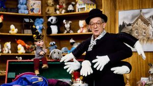 Mr. Dressup, wearing a spider costume, stands in front of his famous Tickle Trunk